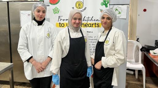 from left to right: Riwa, Hanan and Samira, posing in front of the Access Kitchen initiative’s roll-up.